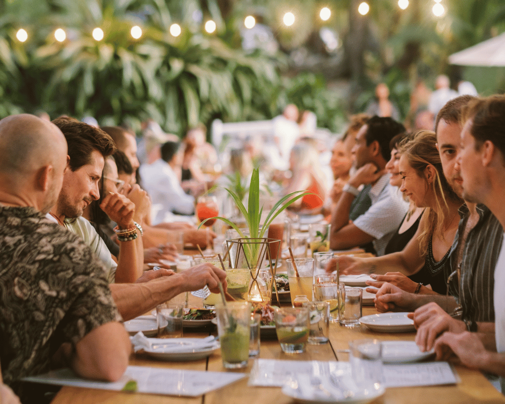 Long communal dinner table under string lights at Nosara
