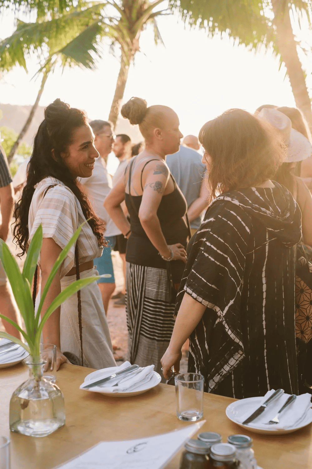 Community gathering under palm trees at a shared outdoor dinner