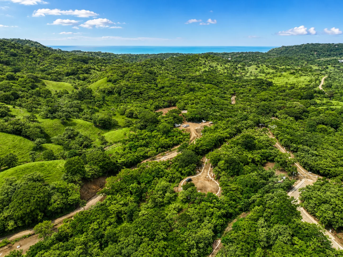 Aerial view of lush green hills and homesites at Shift Esperanza with the ocean beyond