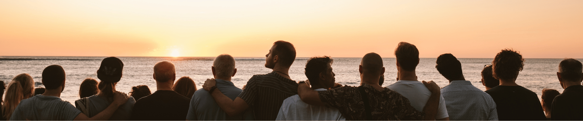 Community gathered together at sunset overlooking the ocean